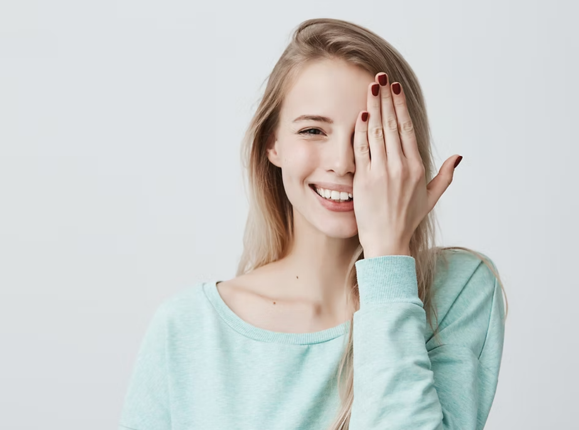 Jeune femme se couvrant un œil de la main, souriante